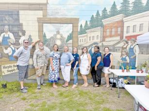Standing in front of the new Jesup mural at Murphy Builders Supply are, from left, Kevin Murphy; plant vendor Marshall McClure; plant-swap hosts Anzley Eisenbeiss, Christy Lynn and Jodi Darley; Jennifer Murphy Reeder; and plant-swap hosts Shavone Isom and Heather Tyre.