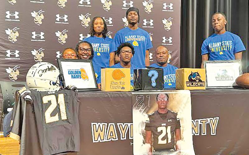 ERIC DENTY / Staff Jarvis Fullmore, center, recently signed to play football with Albany State University in Albany. He is joined by his family; front row, from left, Levi Baisden, Seiarra Bryant (mother), Fullmore, Jarvis Fullmore (father) and Jylan Fullmore and, back row, from left, Destiny Rooks and Quan Wright.