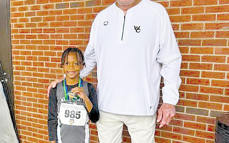 Terrence Ward is all smiles with Wayne County Recreation Department director Speck Echols after setting a state record in the U-8 boys long jump.