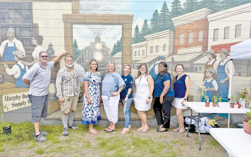 Standing in front of the new Jesup mural at Murphy Builders Supply are, from left, Kevin Murphy; plant vendor Marshall McClure; plant-swap hosts Anzley Eisenbeiss, Christy Lynn and Jodi Darley; Jennifer Murphy Reeder; and plant-swap hosts Shavone Isom and Heather Tyre.
