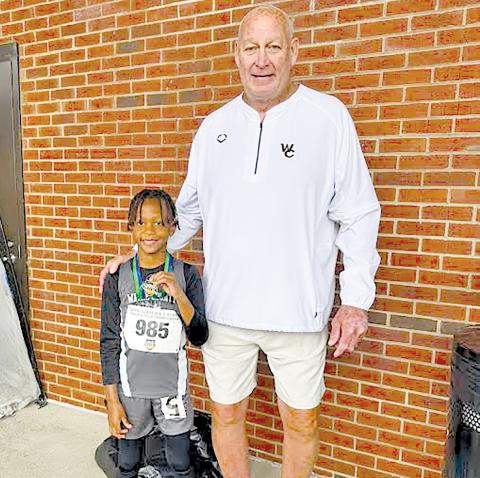 Terrence Ward is all smiles with Wayne County Recreation Department director Speck Echols after setting a state record in the U-8 boys long jump. 