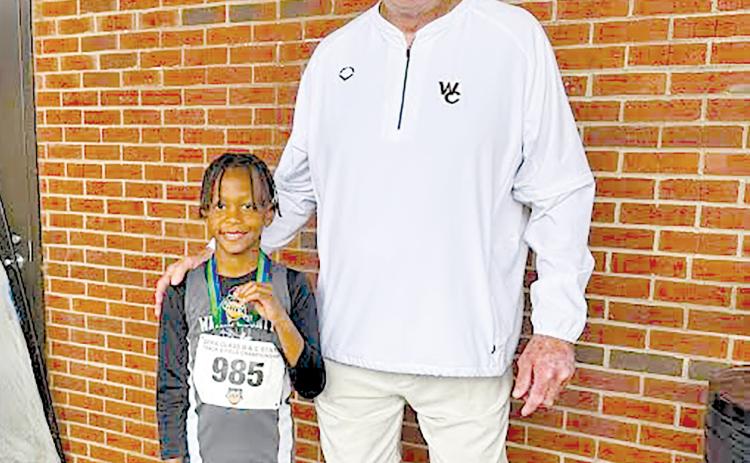 Terrence Ward is all smiles with Wayne County Recreation Department director Speck Echols after setting a state record in the U-8 boys long jump. 