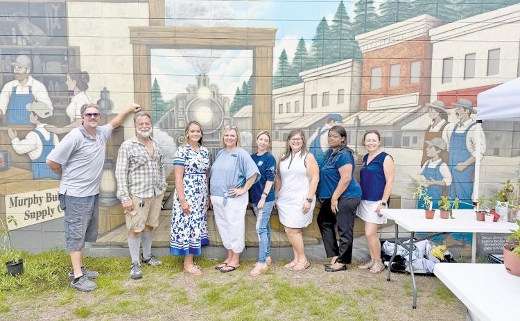 Standing in front of the new Jesup mural at Murphy Builders Supply are, from left, Kevin Murphy; plant vendor Marshall McClure; plant-swap hosts Anzley Eisenbeiss, Christy Lynn and Jodi Darley; Jennifer Murphy Reeder; and plant-swap hosts Shavone Isom and Heather Tyre.